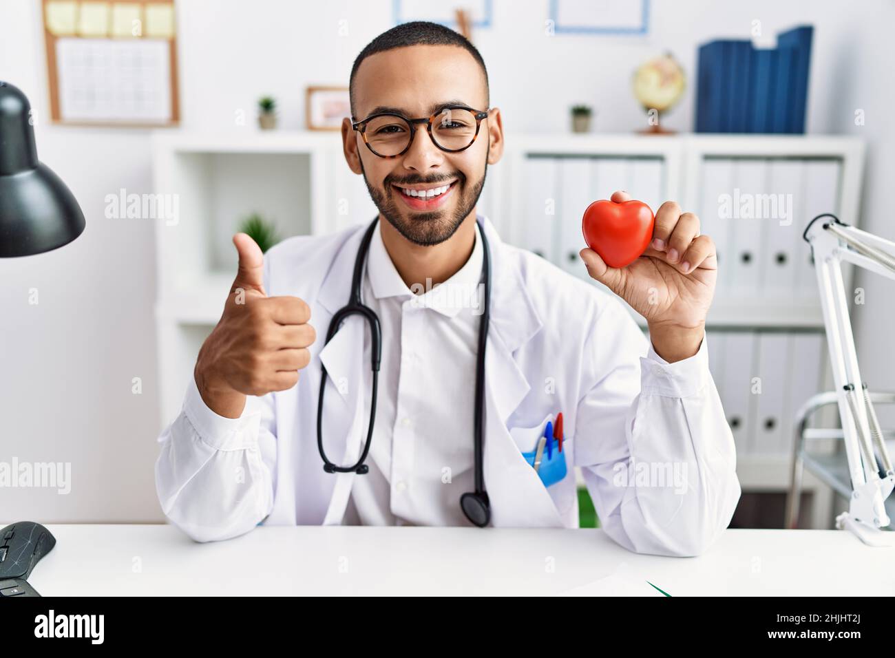 African american doctor man holding heart at medical clinic smiling ...