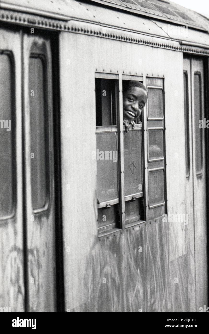 A young lad smiling out of the window of a D train subway car. On an elevated subway in Brooklyn, New York circa 1976. Stock Photo