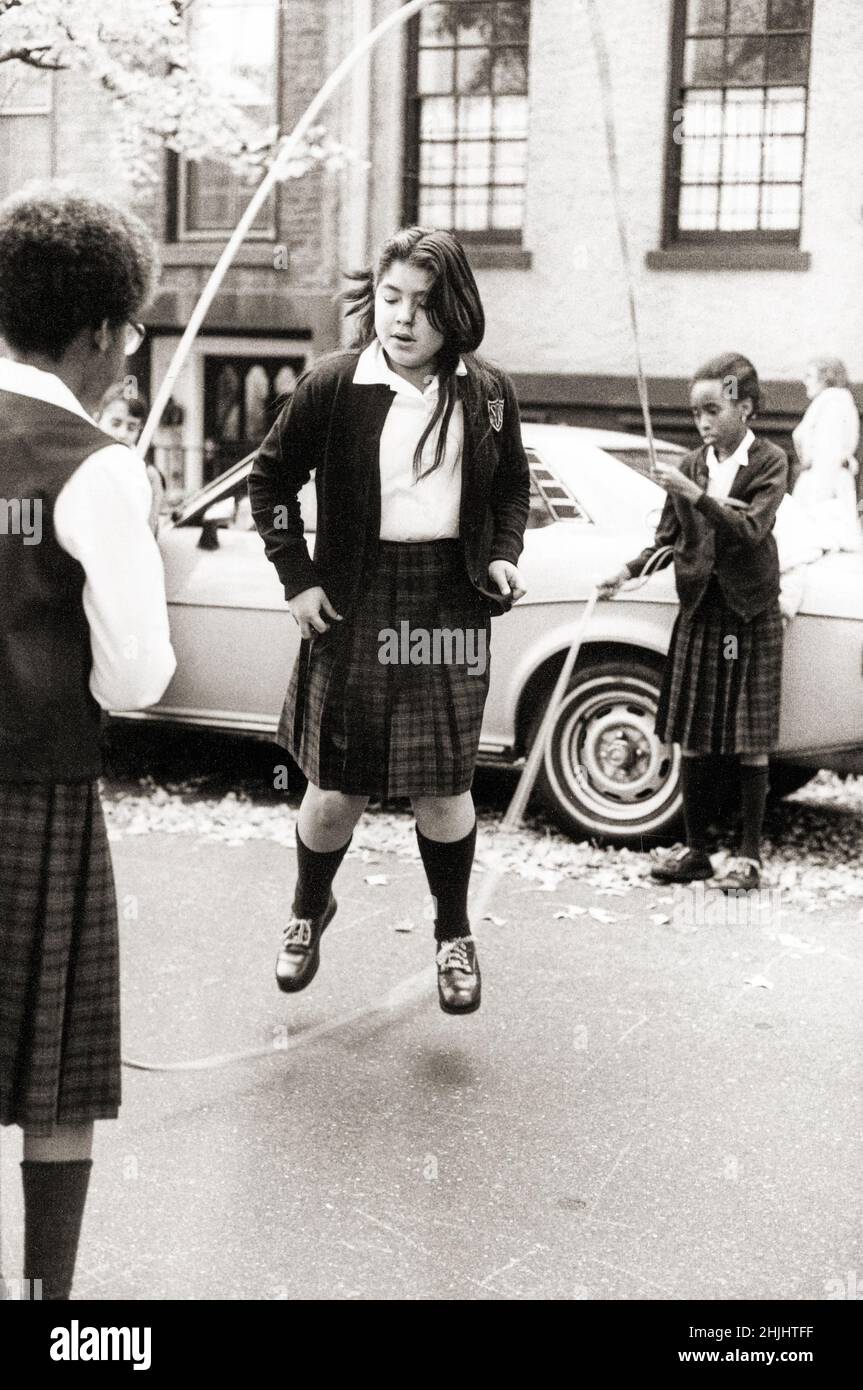 School girls play double Dutch  jump roping on a side street in Brooklyn, New York in the early 1980s. Stock Photo