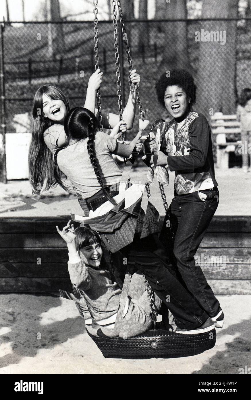 4 girls, likely teenagers, smile and have fun on a tire swing in the 3rd Street playground in Prospect Park, Brooklyn, New York City. Circa 1977. Stock Photo