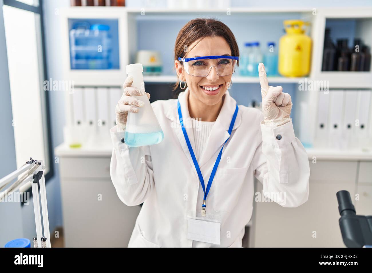 Young brunette woman working at scientist laboratory smiling with an ...