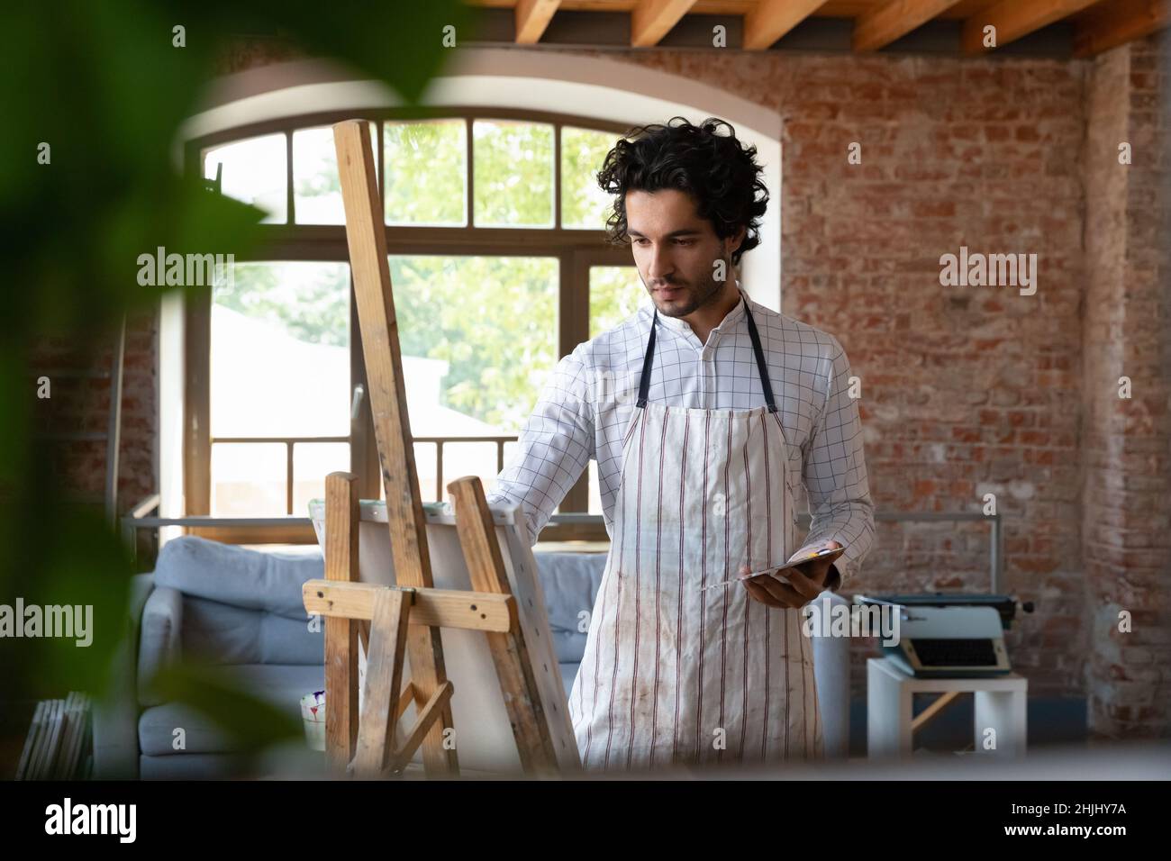 Focused busy attractive young artist student guy training painting