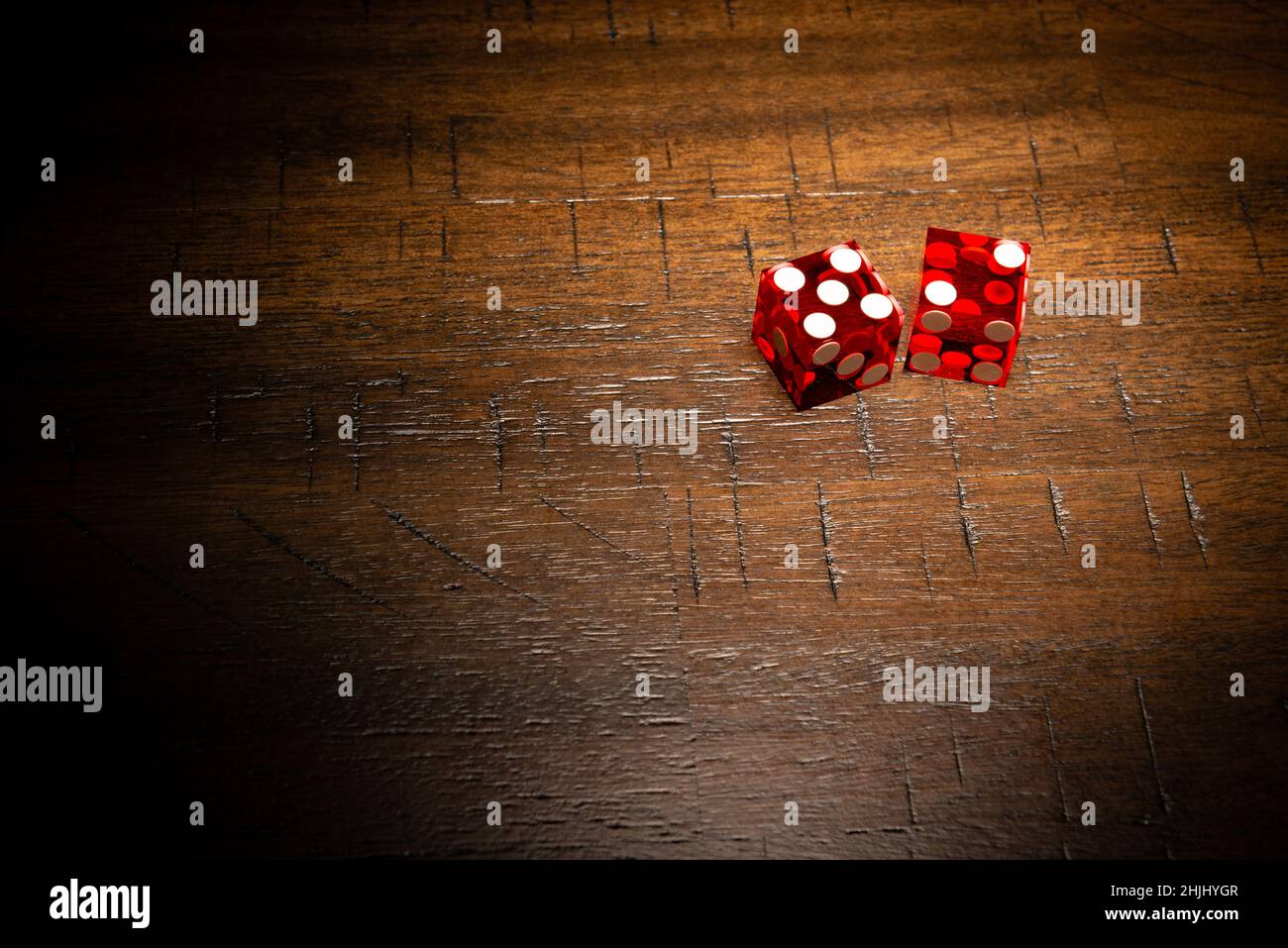 Professional casino-style dice on a wooden table with high-key lighting. Stock Photo