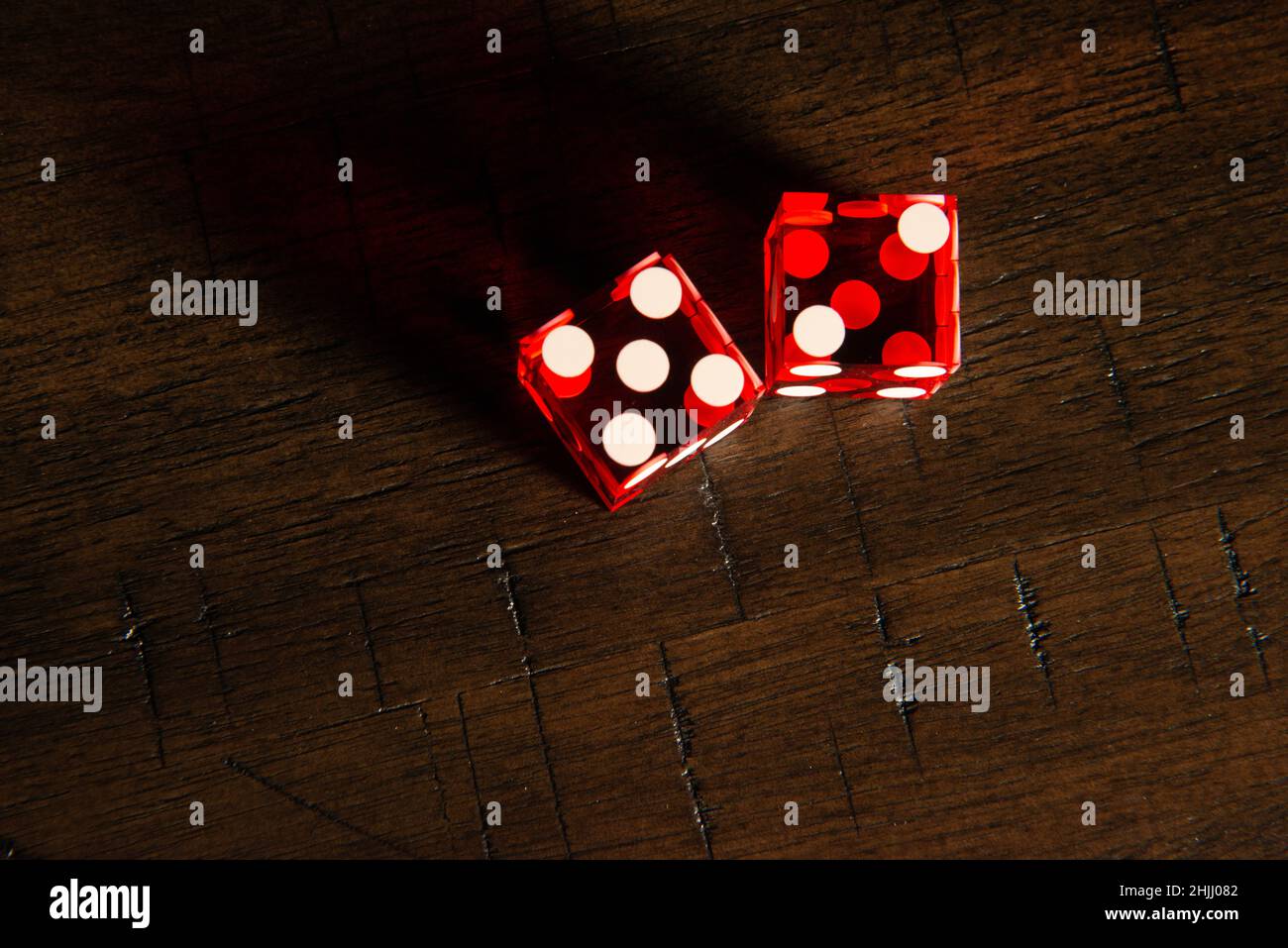 Professional casino-style dice on a wooden table under high-key lighting. Stock Photo