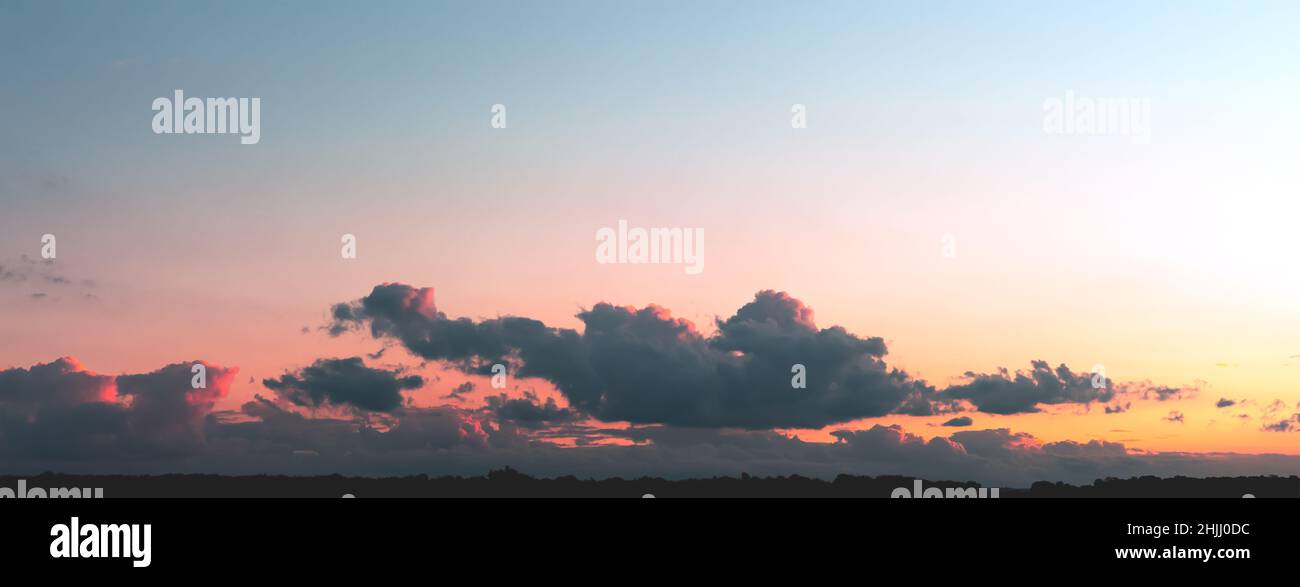 Gray clouds illuminated by the sun on a gradient sky background Stock Photo