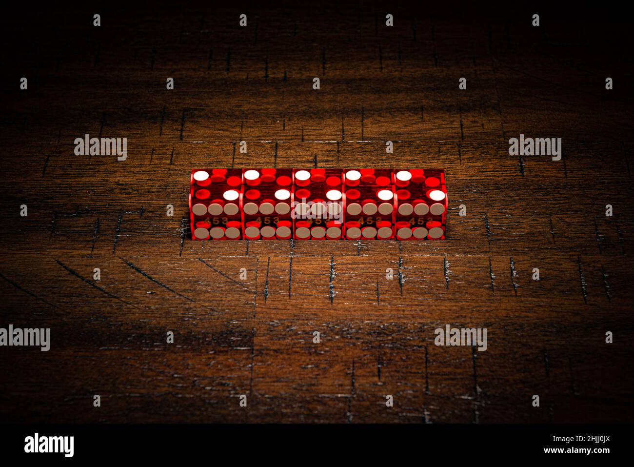 Professional casino-style dice on a wooden table under high-key lighting. Stock Photo