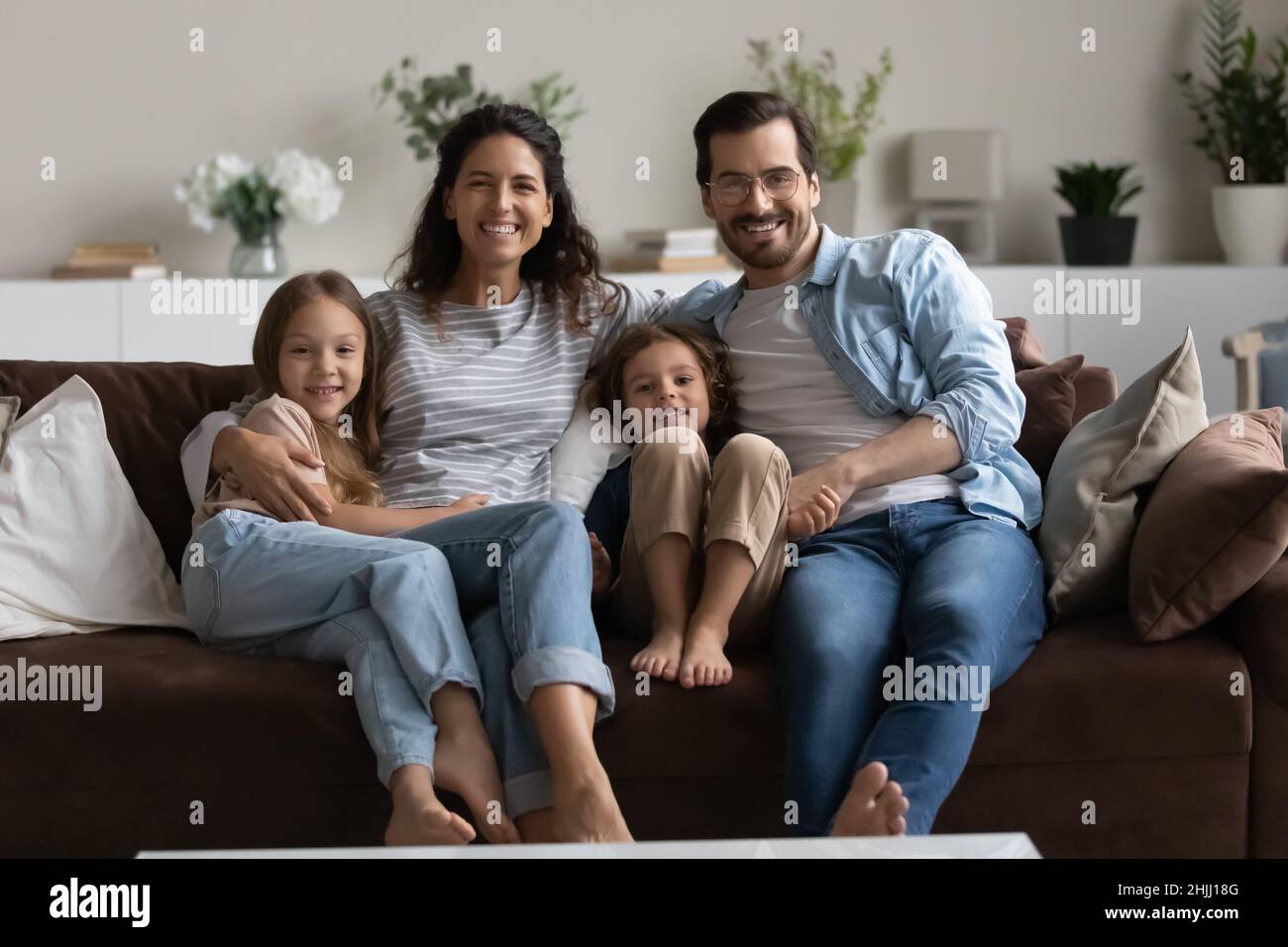 Couple and children sitting on sofa smiling looking at camera Stock Photo