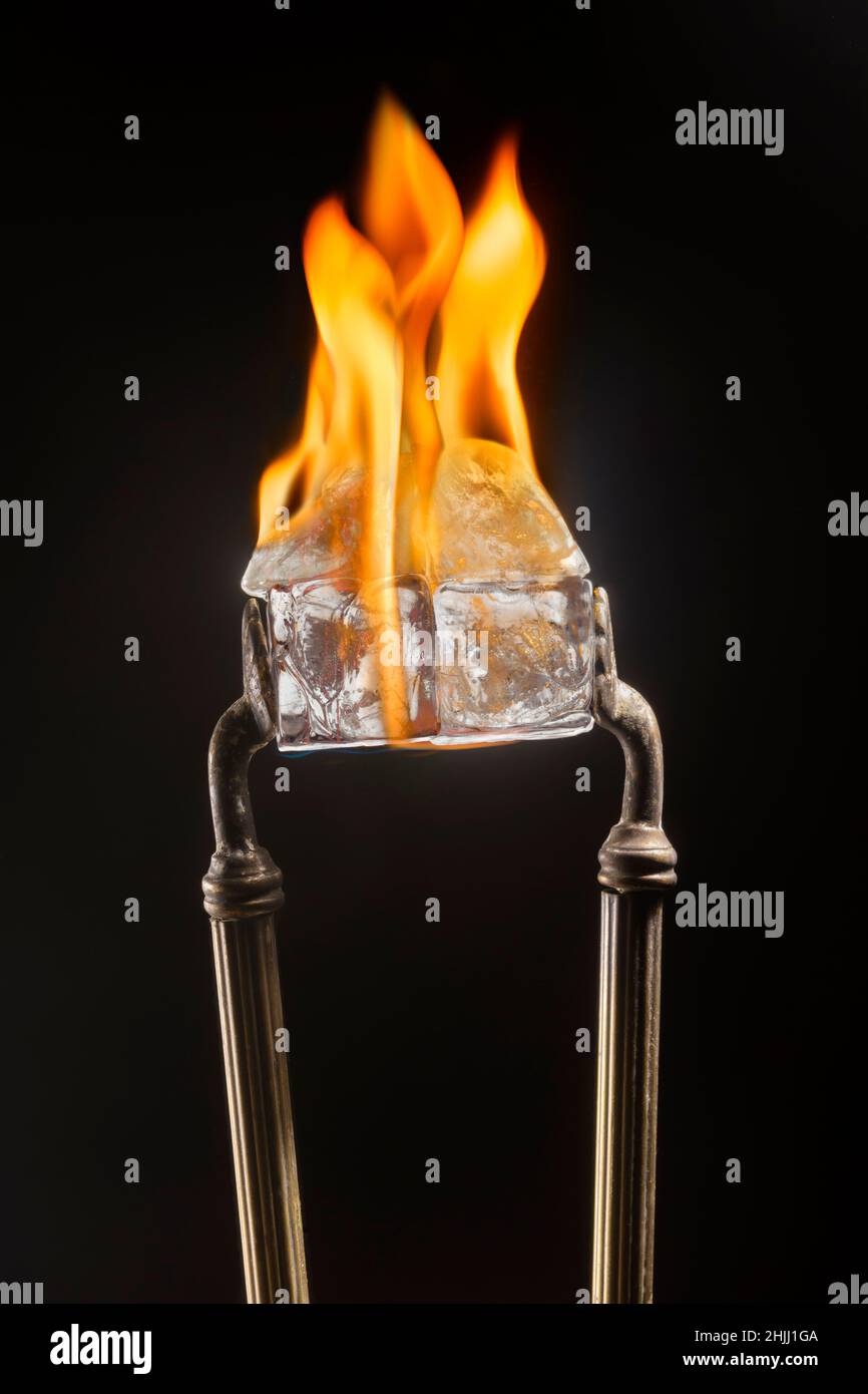 Tongs holding ice cubes while on fire Stock Photo