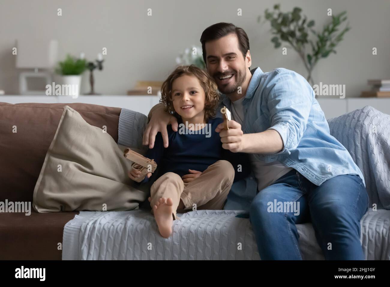 Father and son play toy guns shooting at home Stock Photo