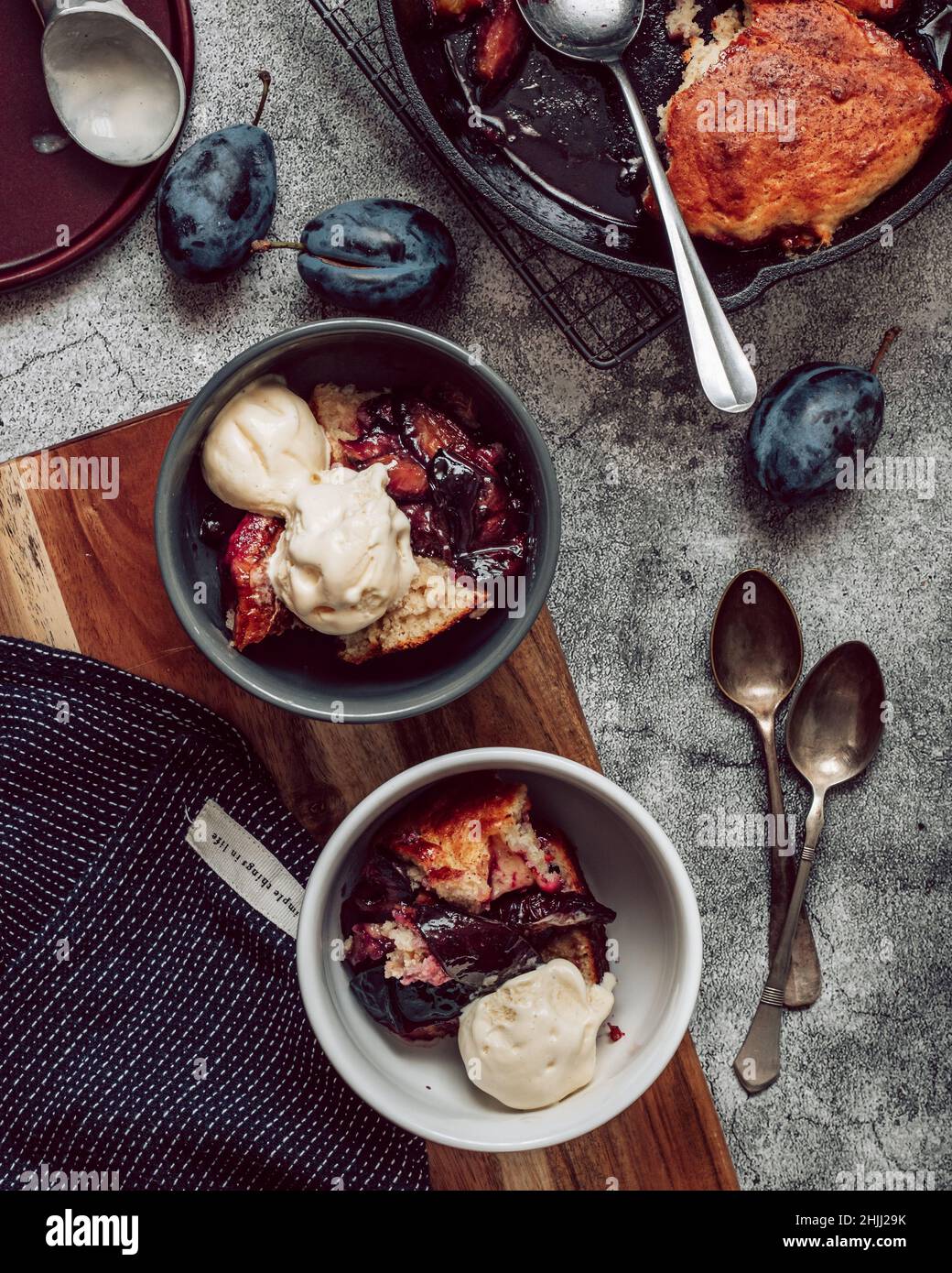 Plum cobbler with vanilla ice cream on a wooden board on gray stone background. top view. flat lay. summer fruits dessert Stock Photo