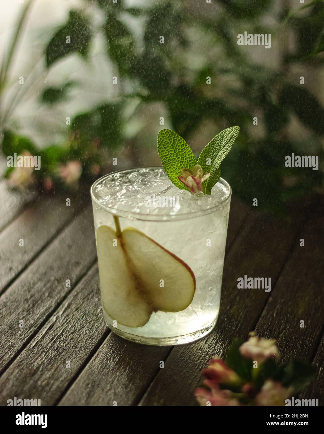 summer cocktail decorated with mint, lemon and slices pears on a wooden table on a floral background Stock Photo