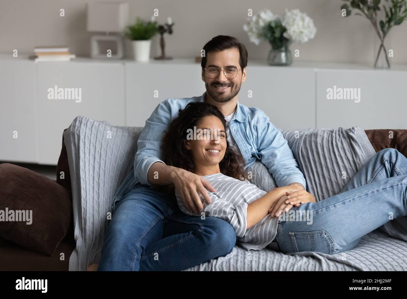 Couple relaxing on sofa hugging posing looking at camera Stock Photo