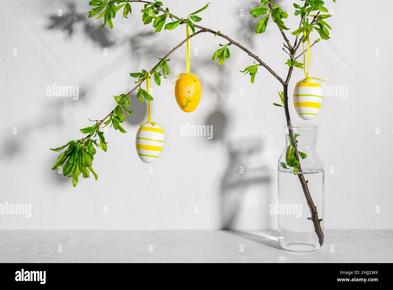 Vase with tree branches decorated with colorful Easter eggs Stock Photo