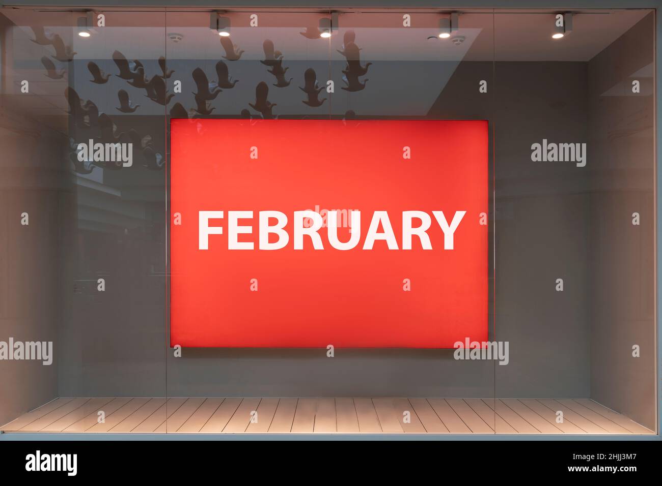 The month of February is a word on a red banner in the window of a boutique store behind glass. the last month of winter. Stock Photo