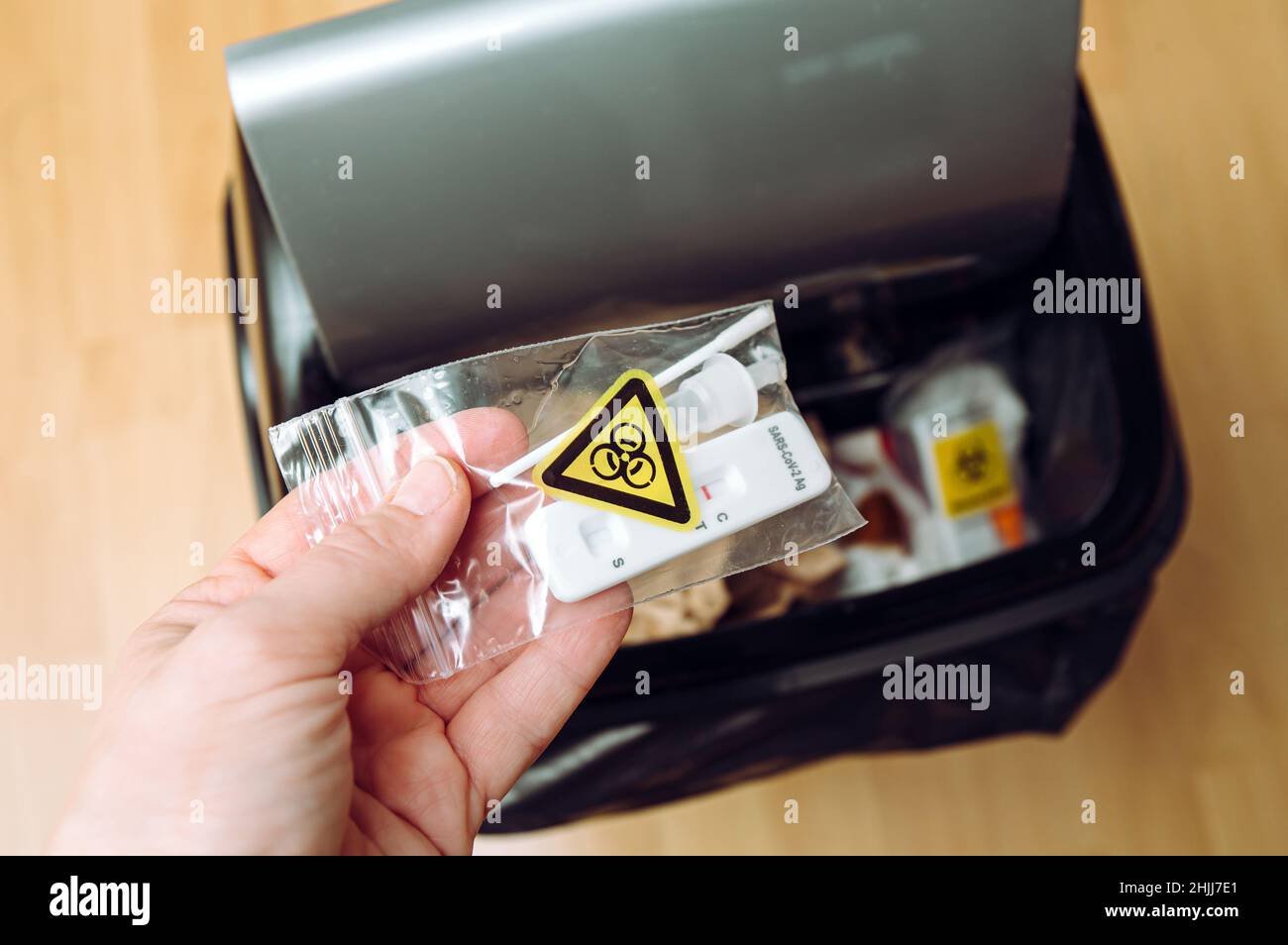 Safe handling and management of rapid antigen COVID-19 testing waste concept. Person hand throw away pieces of antigen test kit sealed in plastic bag. Stock Photo
