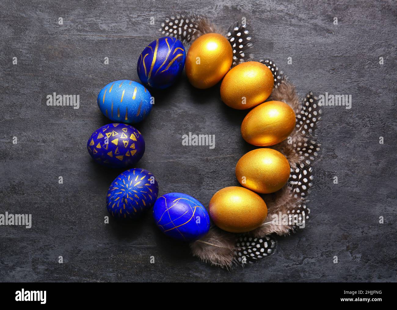 Frame made of stylish Easter eggs and feathers on dark background Stock Photo