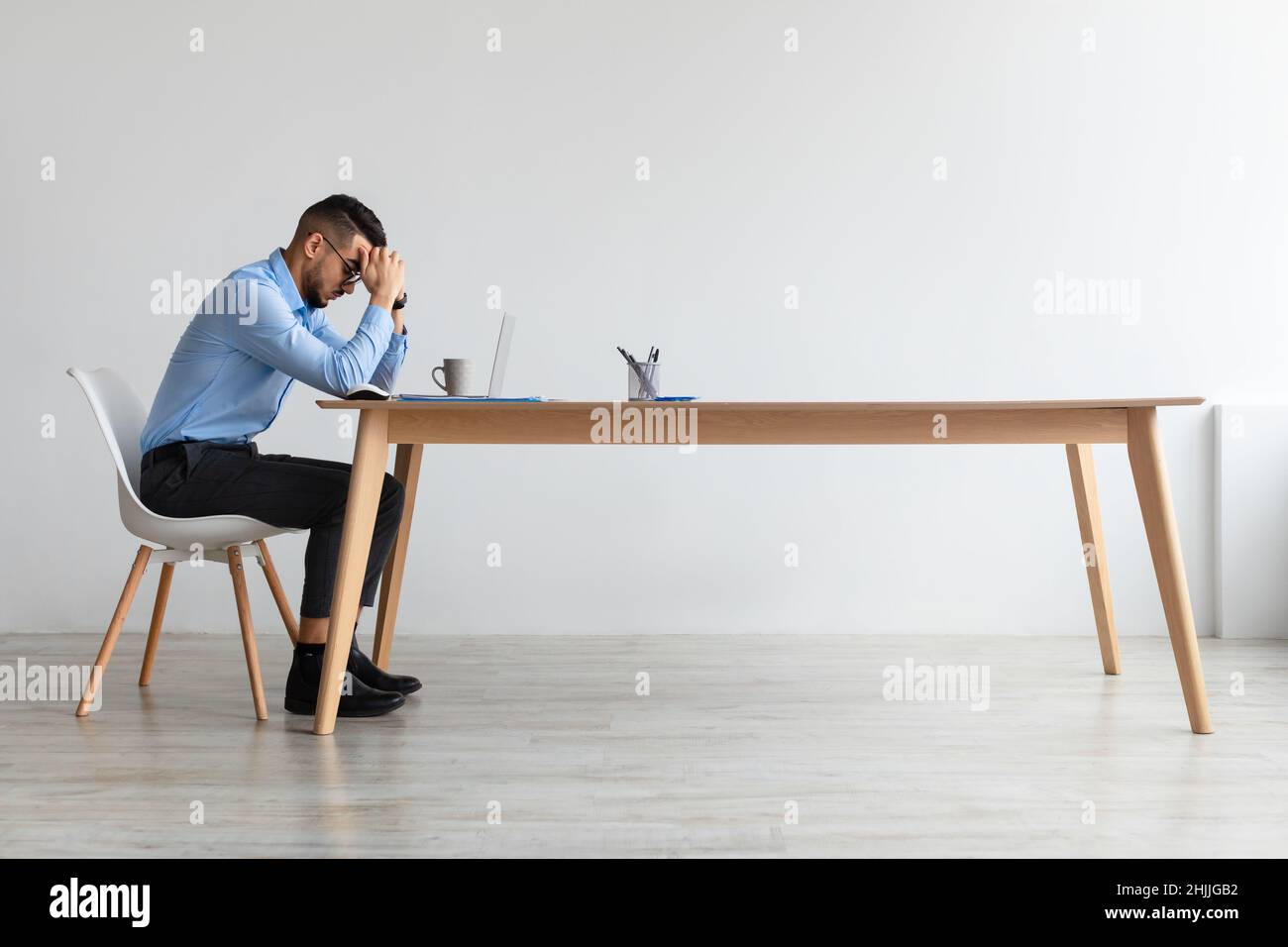 Arab man suffering from headache or migraine at work Stock Photo