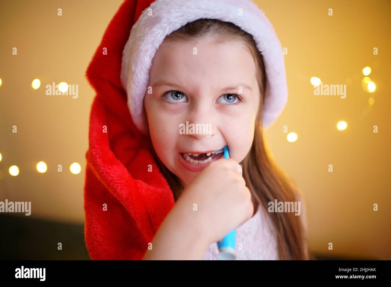 little girl brushing her teeth in Santa hat Stock Photo Alamy
