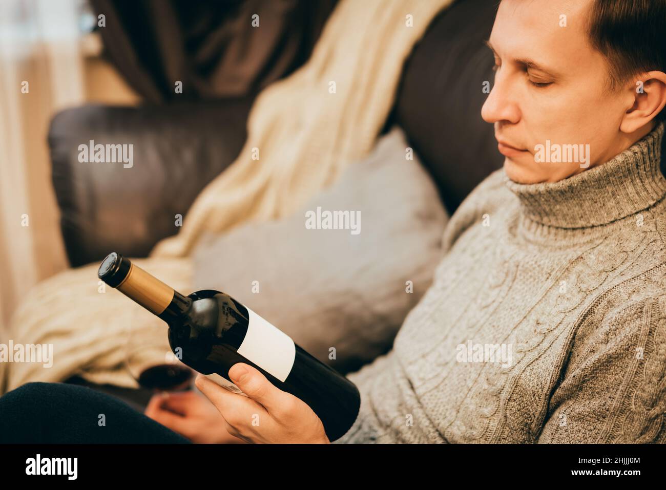 Man holding a red wine bottle in his hand and plan to relax at home