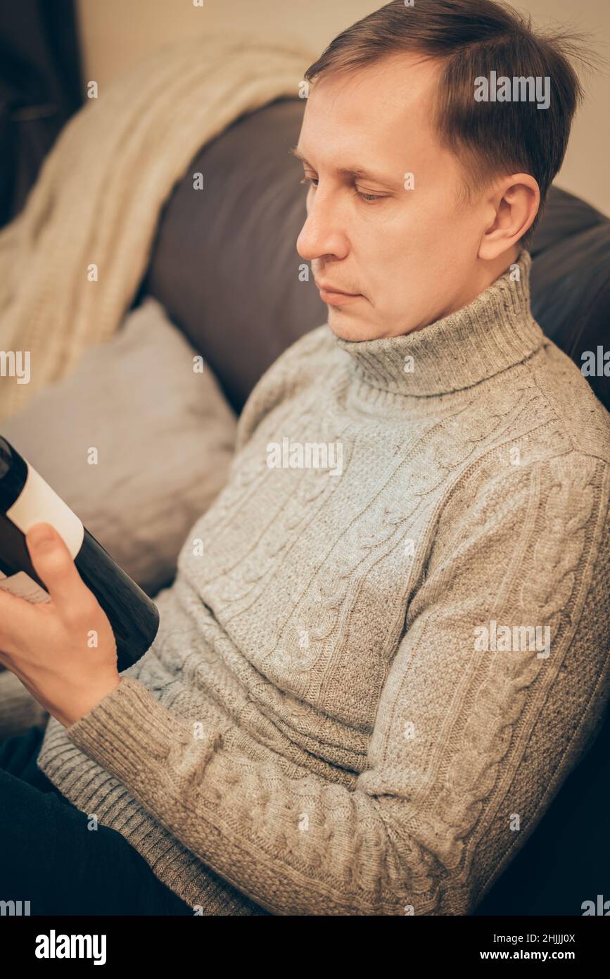 Man holding a red wine bottle in his hand and plan to relax at home