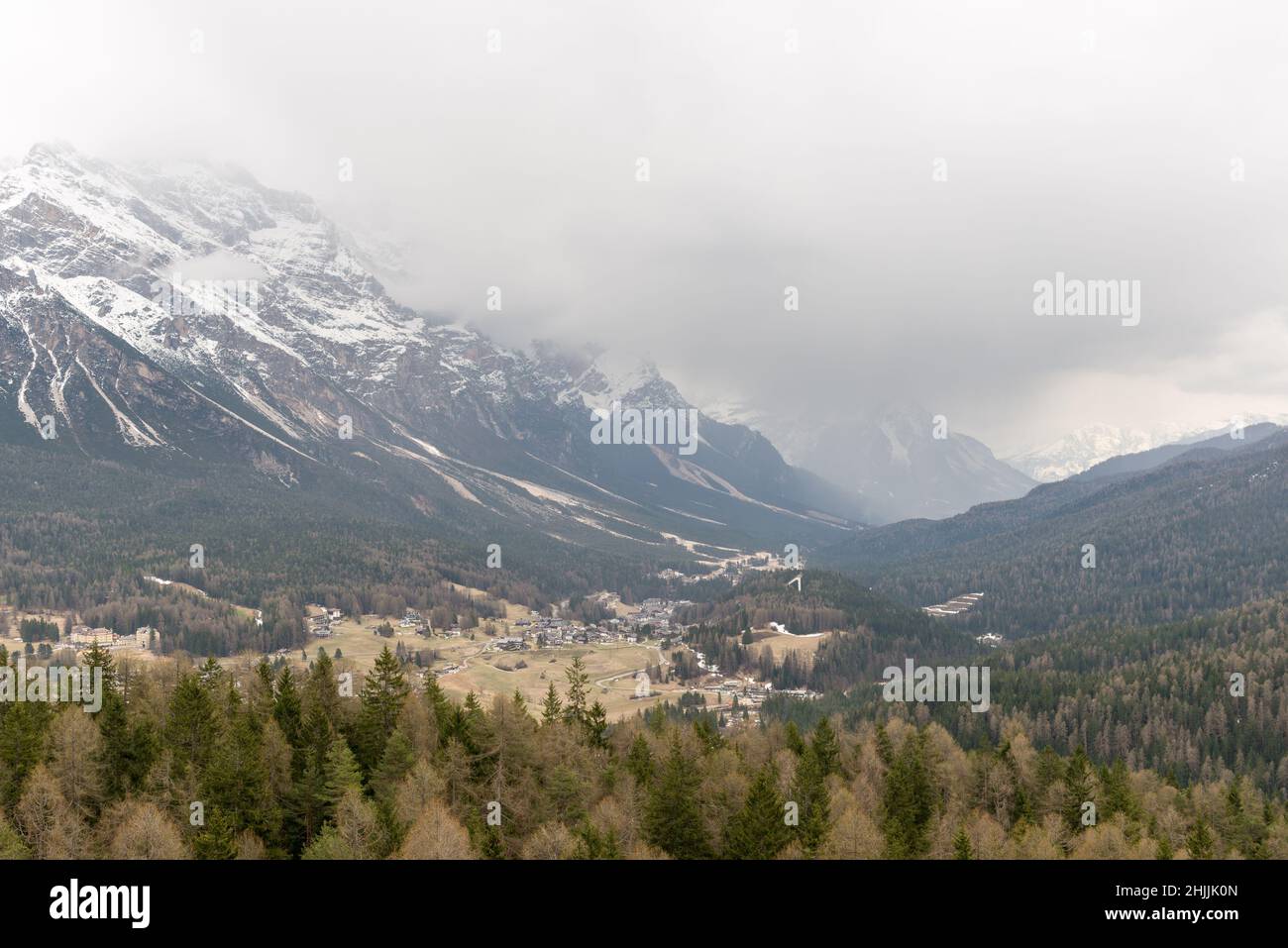 View over the valley in Dolomites, Northern Italy with mountain tops covered in mist. Stock Photo