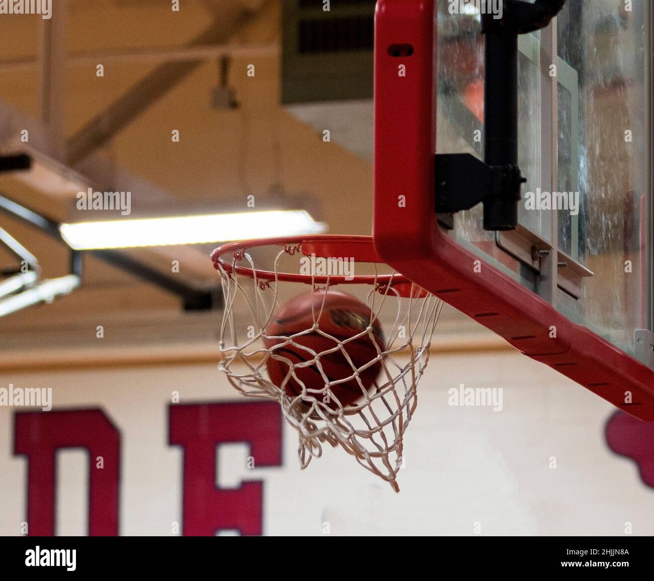 A basketball shot is made with the ball going though the net during a indoor game. Stock Photo