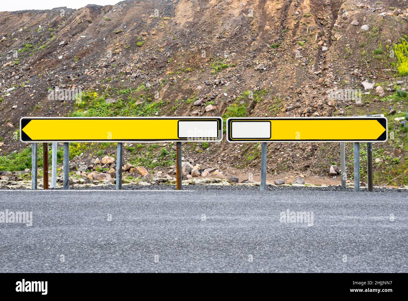 Blank road signs pointing at opposite directions at a crossroads in the countryside. Copy space. Stock Photo