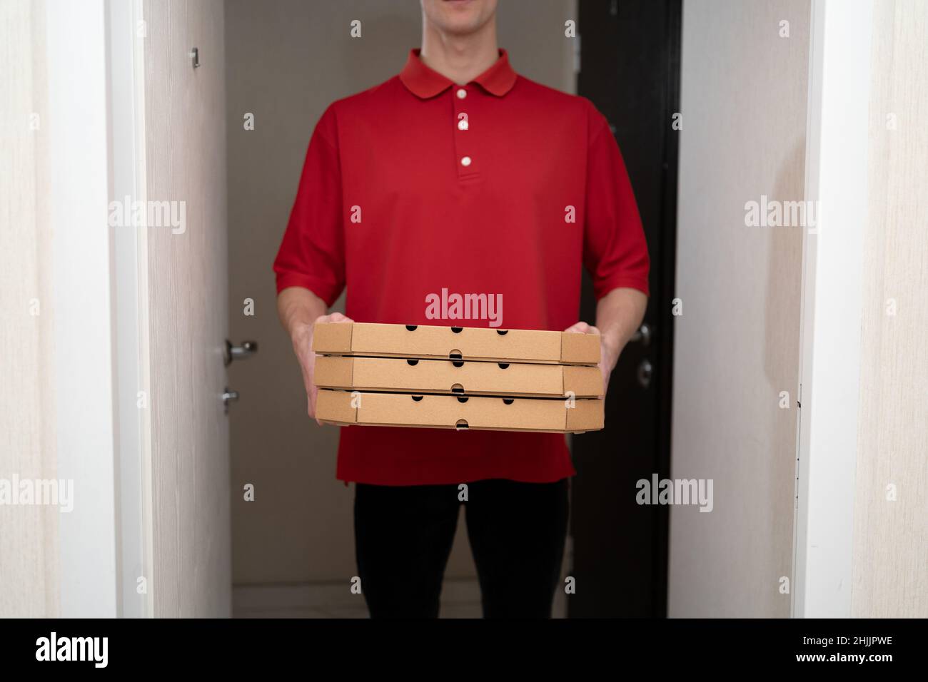 Pizza delivery courier man in red uniform, boxes from a pizzeria in the