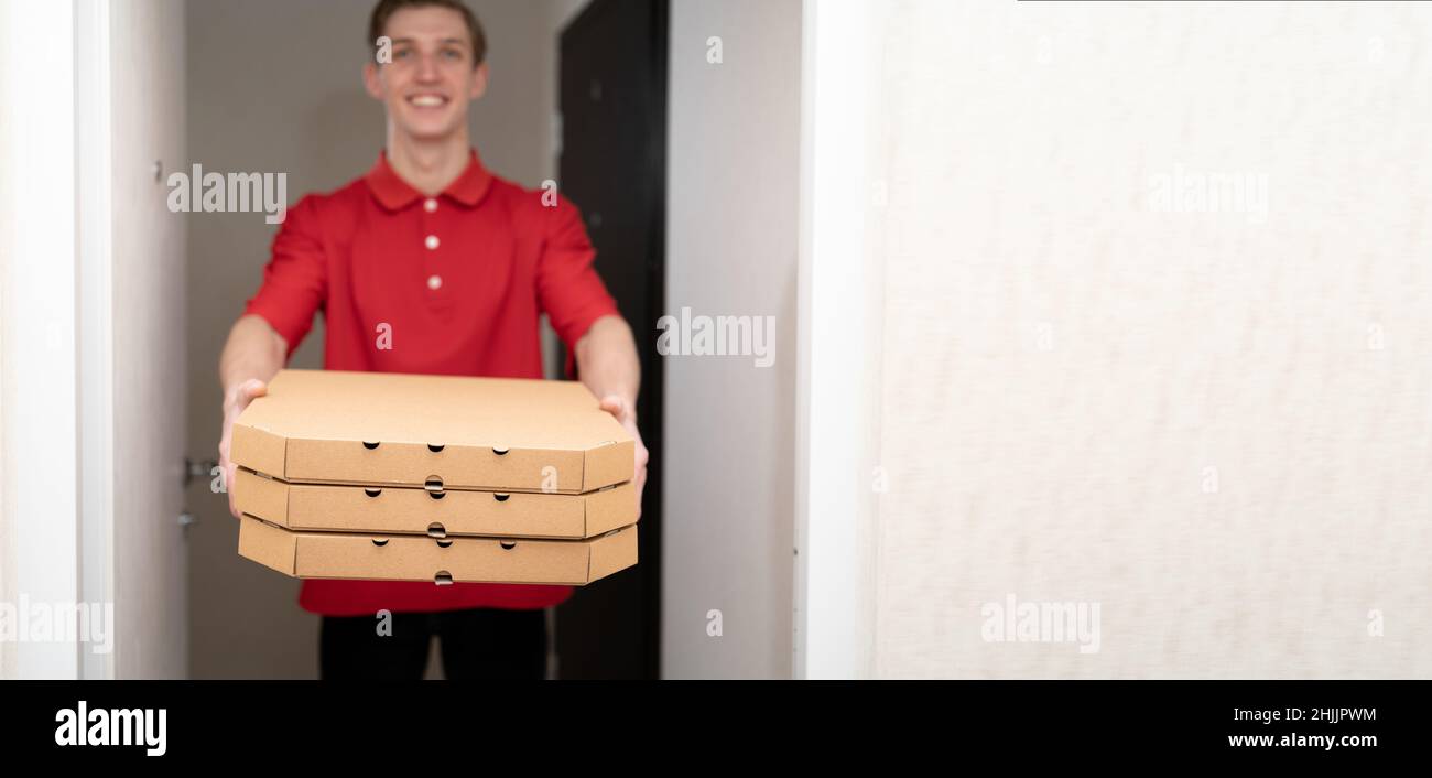 Pizza delivery home, deliveryman with pizza boxes at the door, food delivery service courier, banner Stock Photo