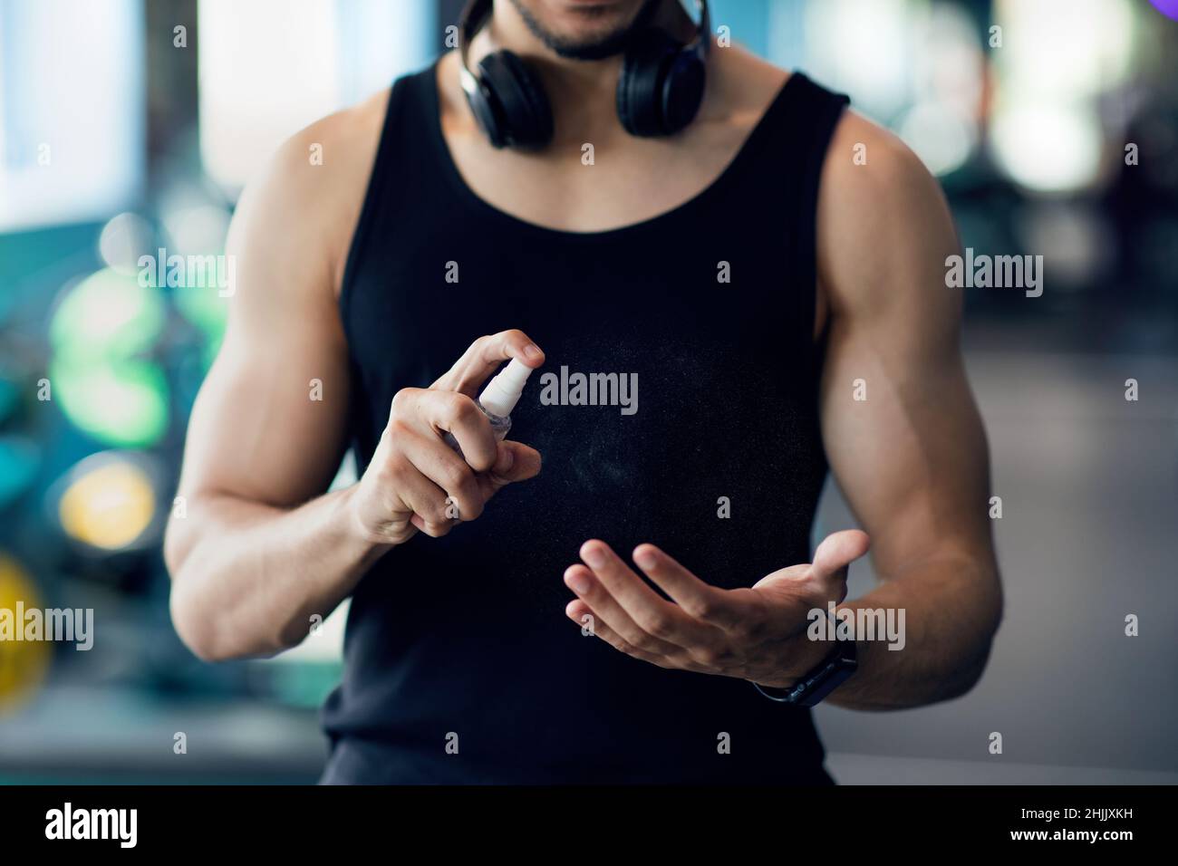 Unrecognizable Muscular Man Applying Disinfectant Spray On Hands Before Training At Gym Stock Photo