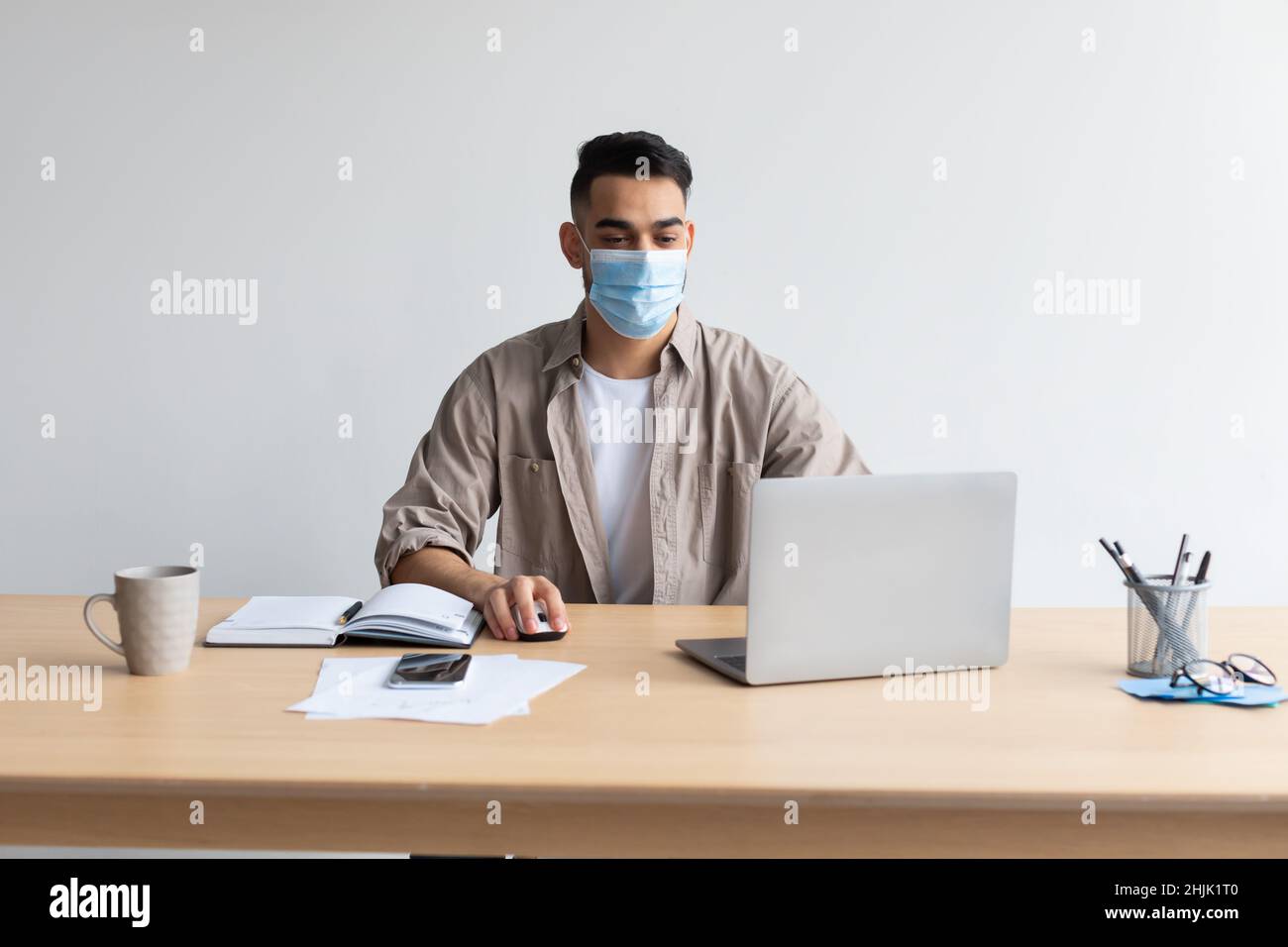 Man in disposable facemask working on pc at home office Stock Photo