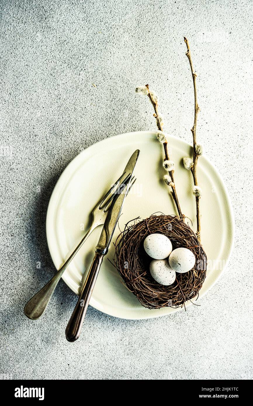 Overhead view of a place setting with Easter eggs in a bird's nest on a table Stock Photo