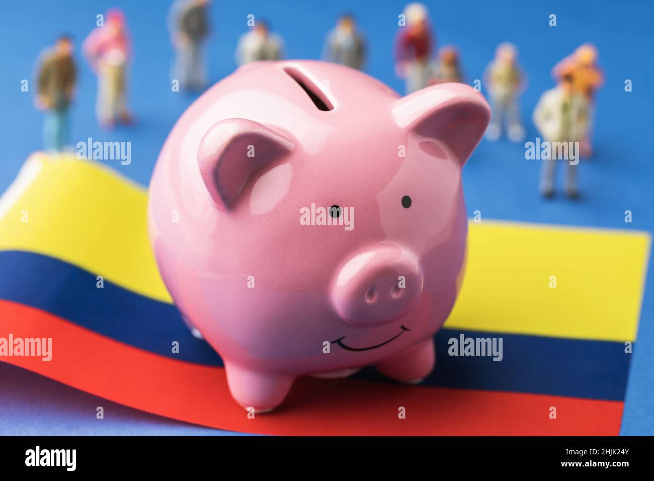Piggy bank, Colombian flag and plastic toy people on a colored background, a concept on the topic of income of the population of Colombia Stock Photo