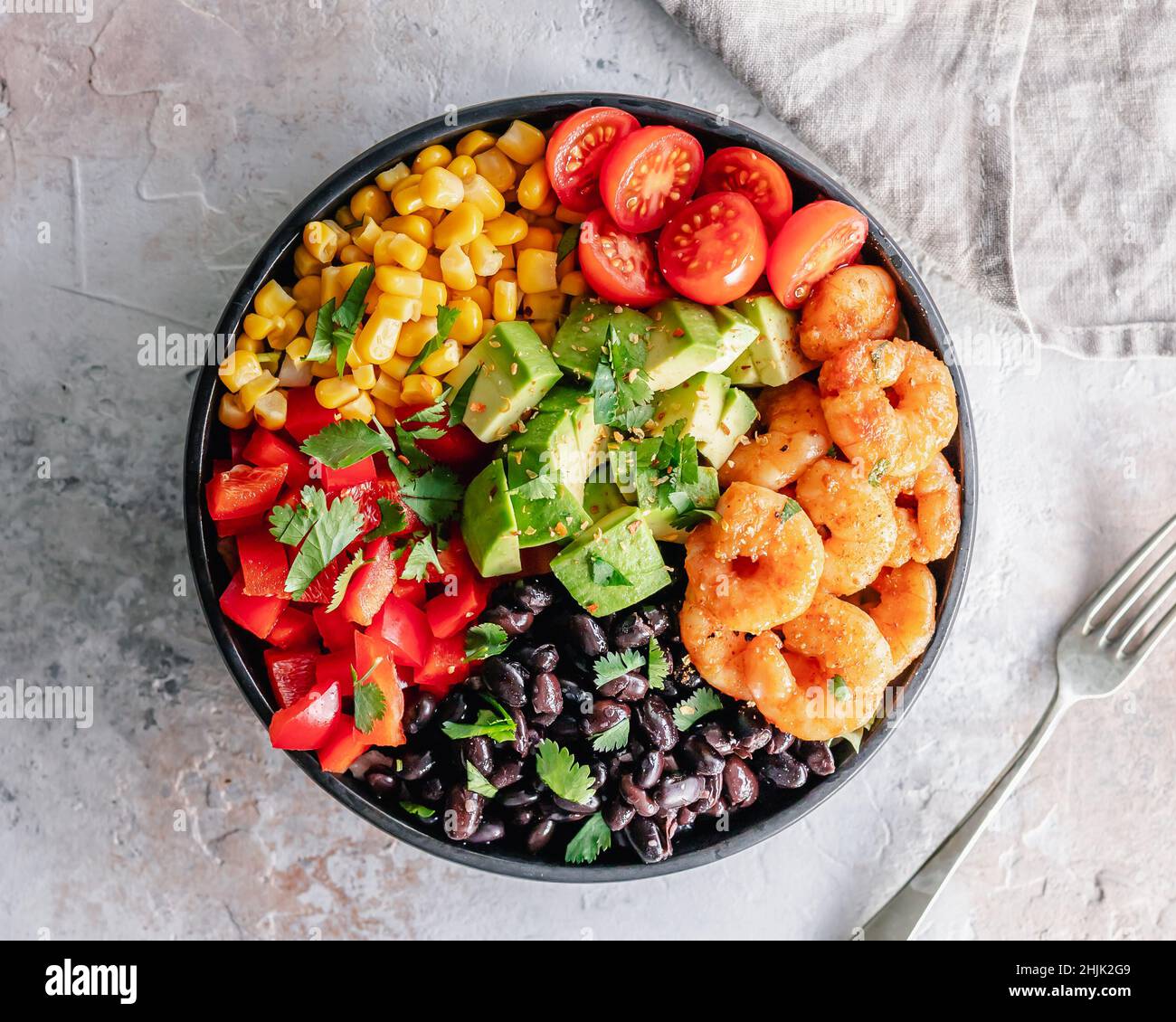 Overhead view of a Mexican shrimp salad with sweetcorn, red peppers, black beans, tomatoes, avocado and coriander Stock Photo