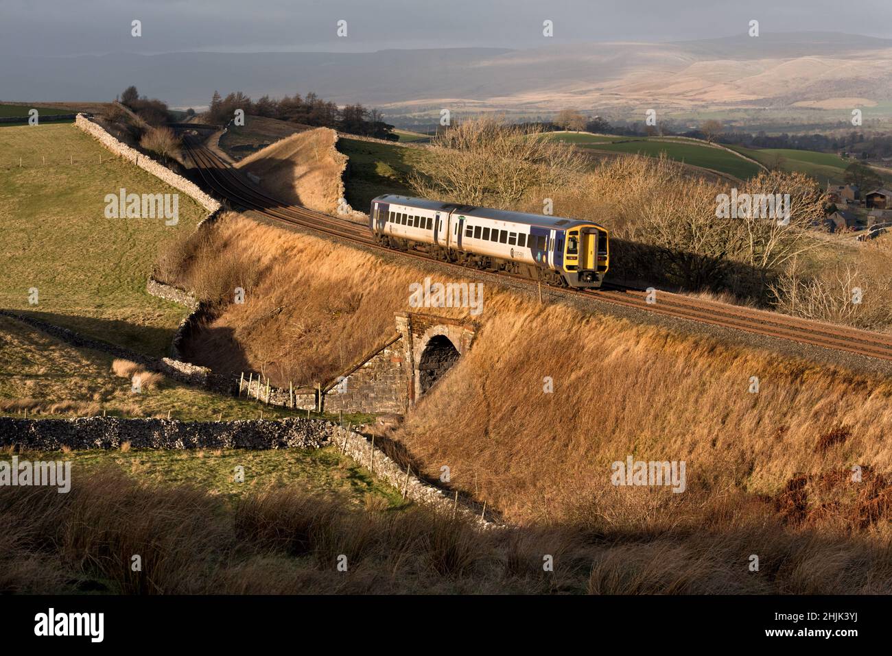 A Sprinter passenger train heads north on the Settle-Carlisle railway line late on a Winter afternoon. Seen here at Birkett Common near Kirkby Stephen. Stock Photo