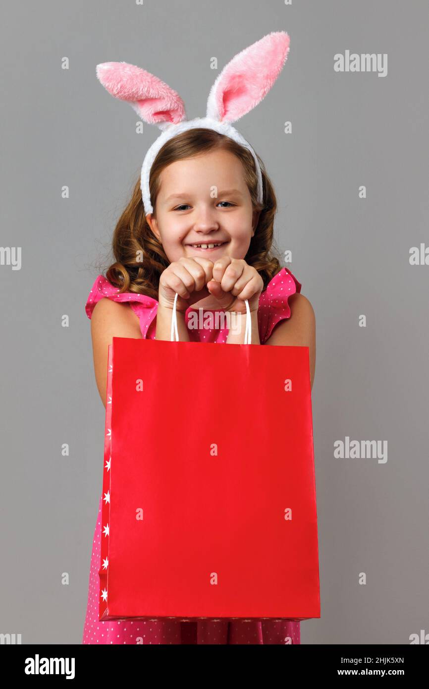 Easter. A little girl in a pink polka dot dress holds a shopping bag in ...
