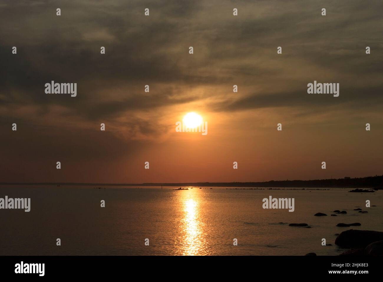 Scenic sunset over the sea. Reflection of the sun in water. The sky is painted with bright colors. Sunset beach in a summer evening. Gulf of Finland, Stock Photo