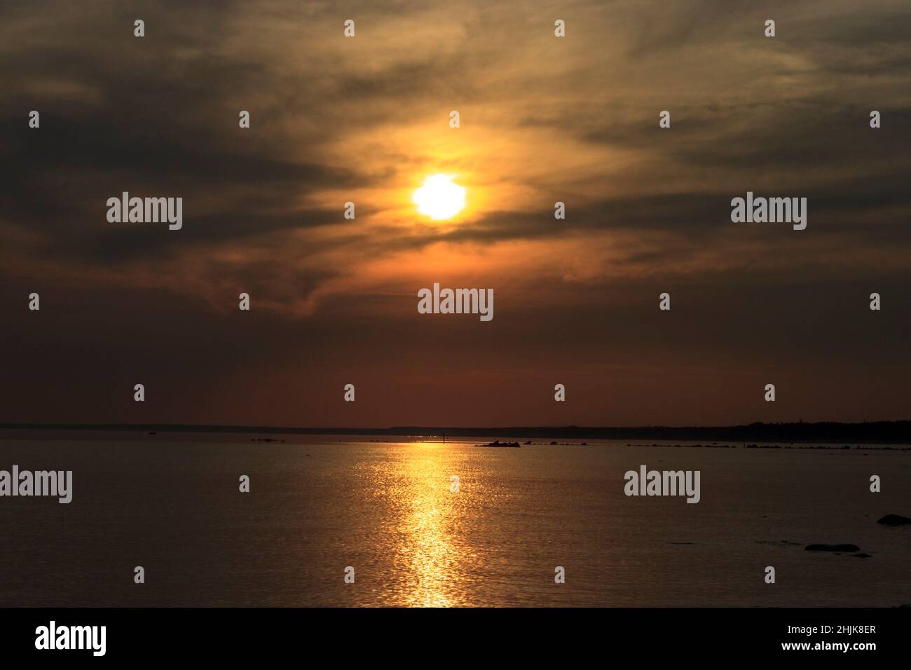 Scenic sunset over the sea. Reflection of the sun in water. The sky is painted with bright colors. Sunset beach in a summer evening. Gulf of Finland, Stock Photo