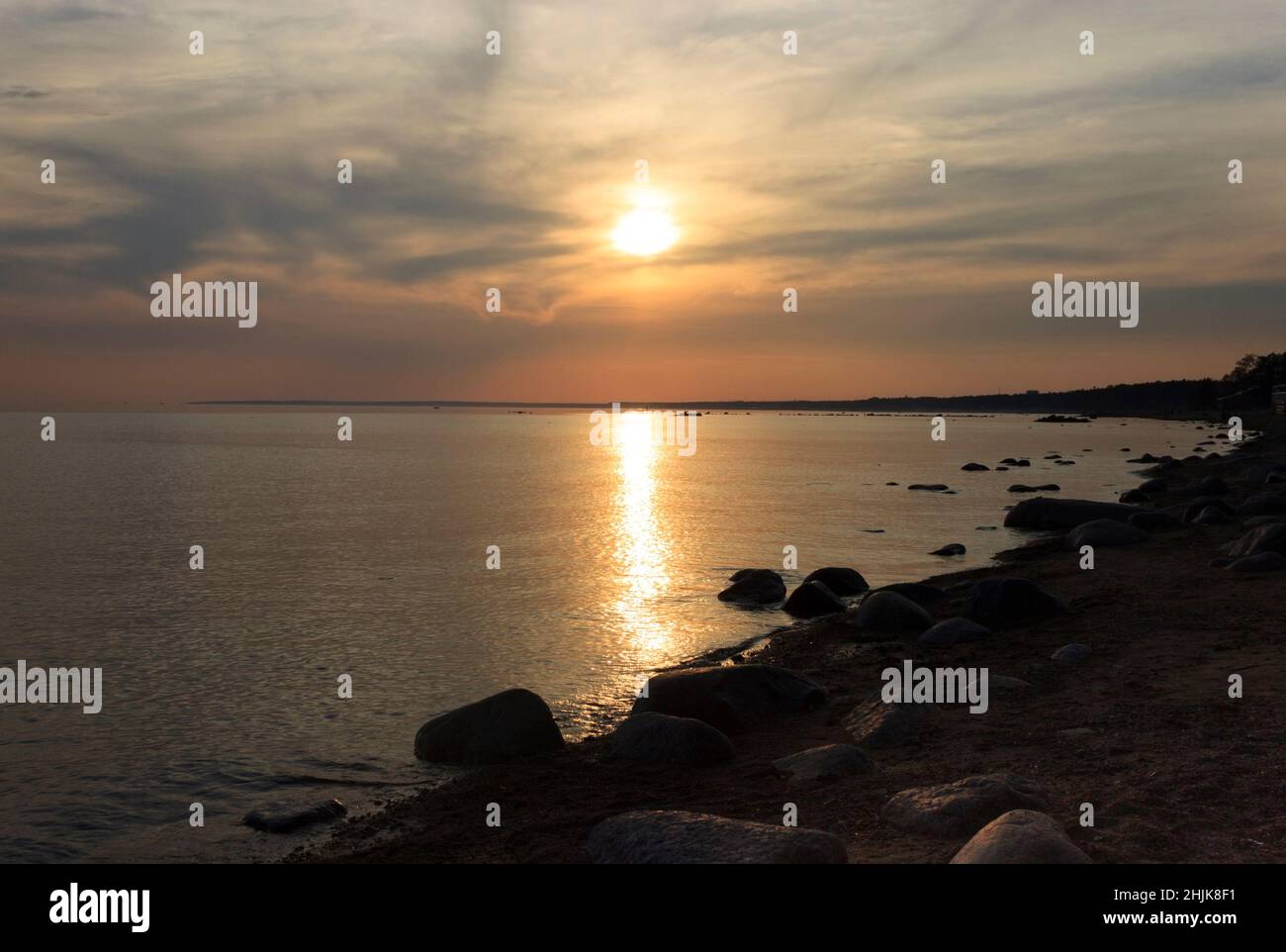 Scenic sunset over the sea. Reflection of the sun in water. The sky is painted with bright colors. Sunset beach in a summer evening. Gulf of Finland, Stock Photo