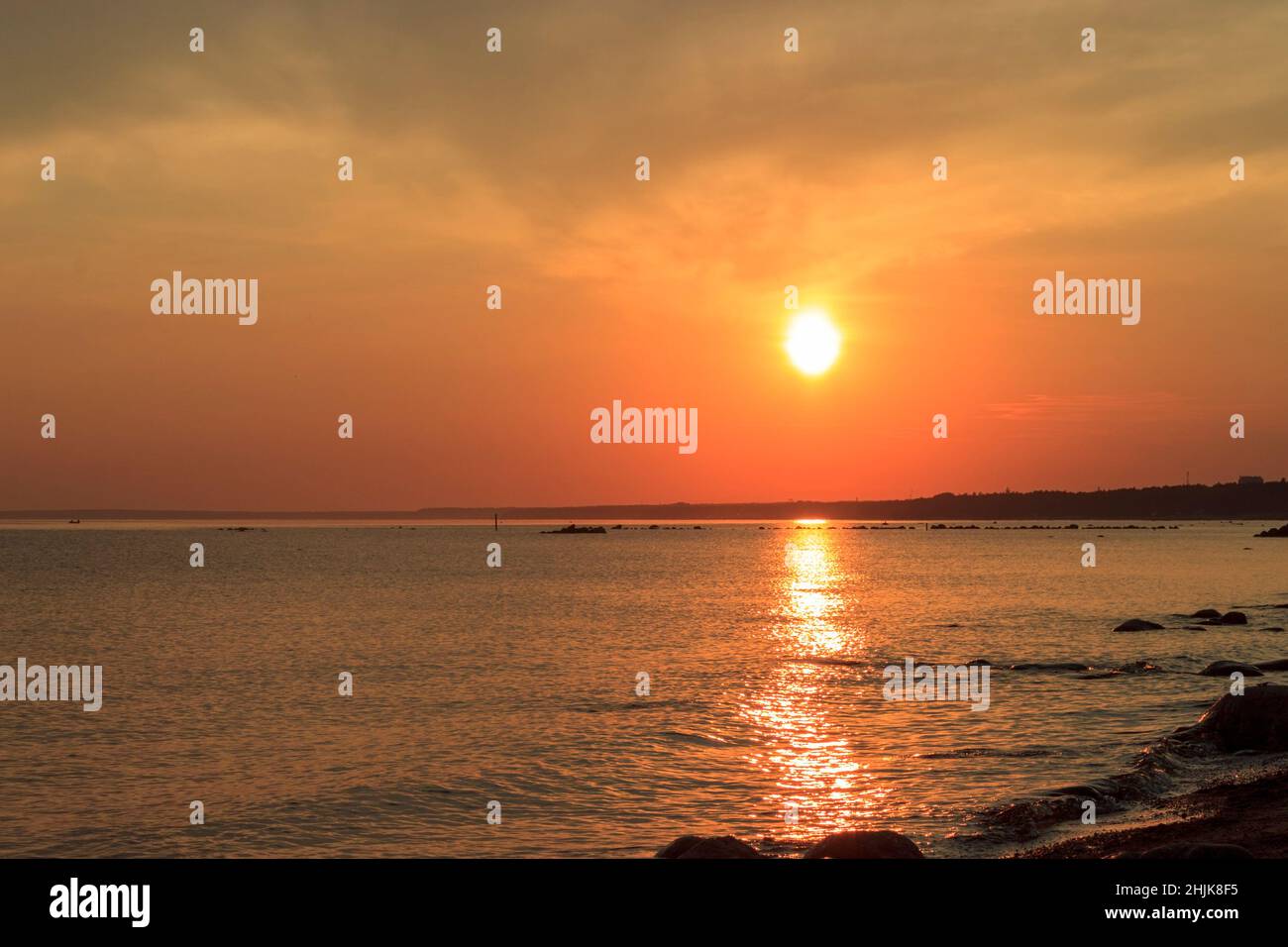 Scenic sunset over the sea. Reflection of the sun in water. The sky is painted with bright colors. Sunset beach in a summer evening. Gulf of Finland, Stock Photo
