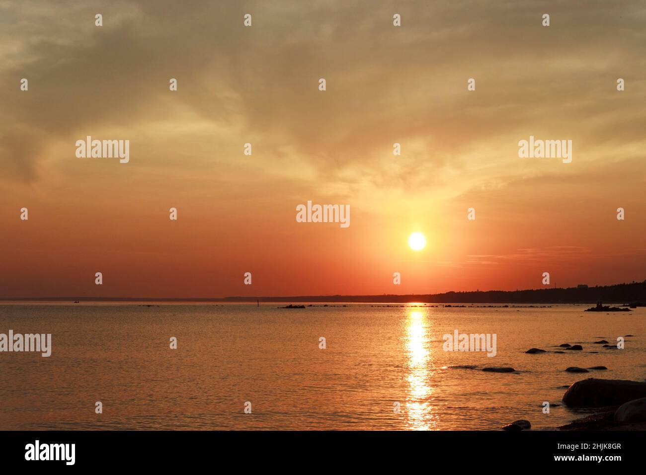 Scenic sunset over the sea. Reflection of the sun in water. The sky is painted with bright colors. Sunset beach in a summer evening. Gulf of Finland, Stock Photo