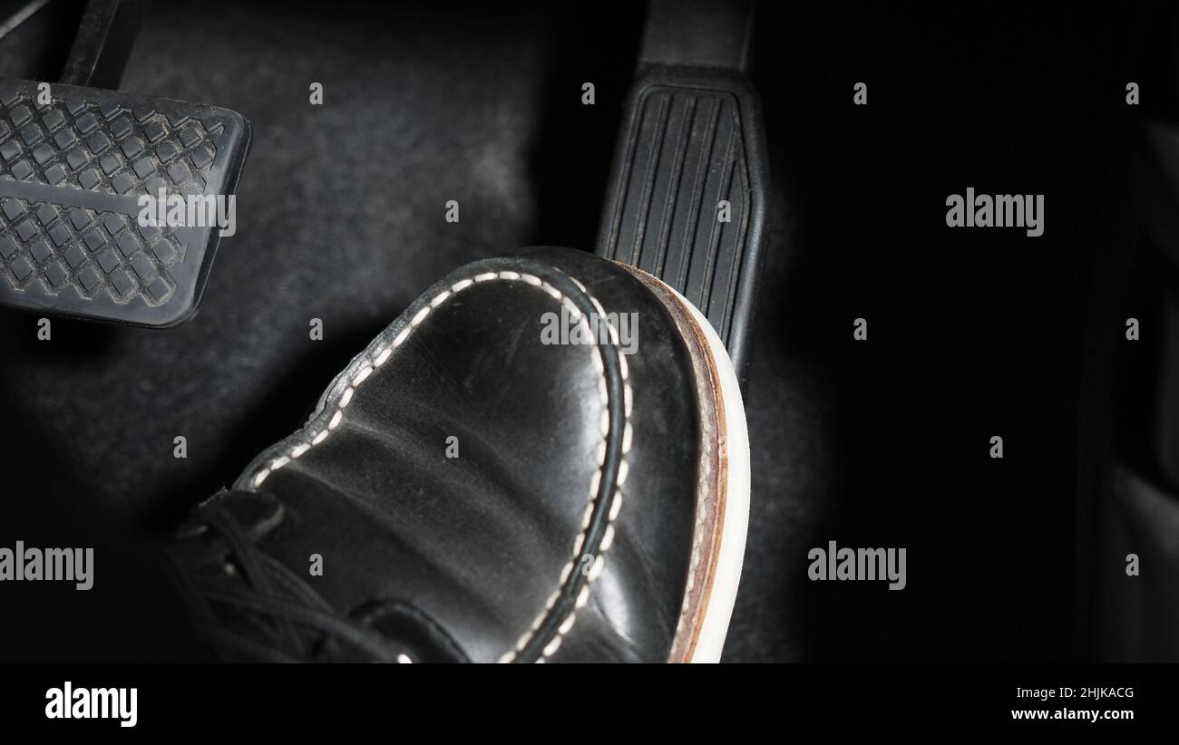 Accelerate and Brake. Foot pressing foot pedal of a car to drive ahead