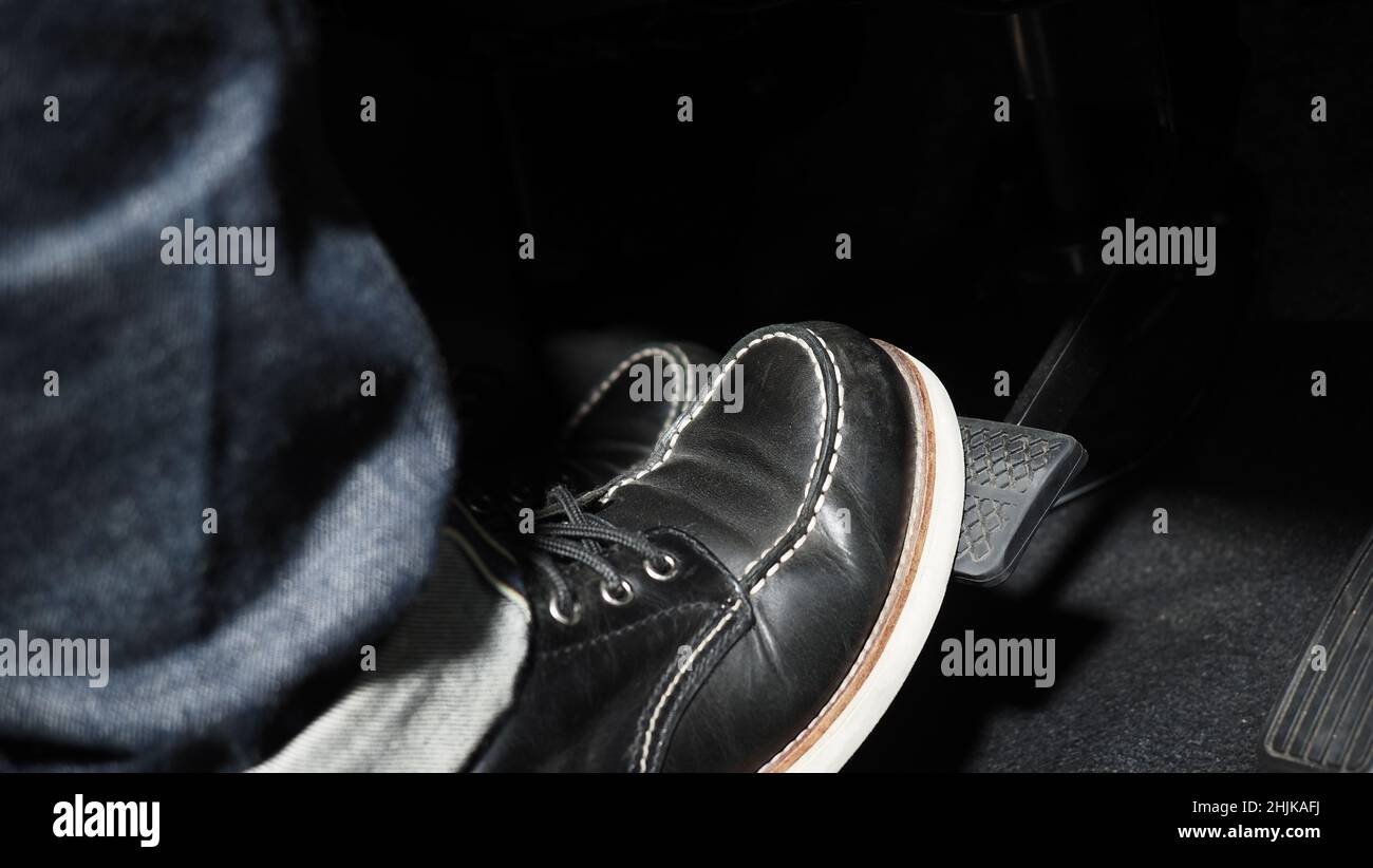 Accelerate and Brake. Foot pressing foot pedal of a car to drive ahead