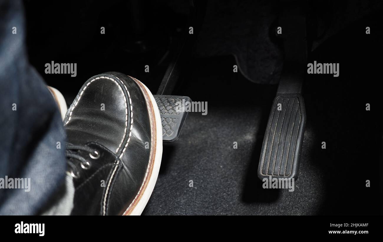Accelerate and Brake. Foot pressing foot pedal of a car to drive ahead