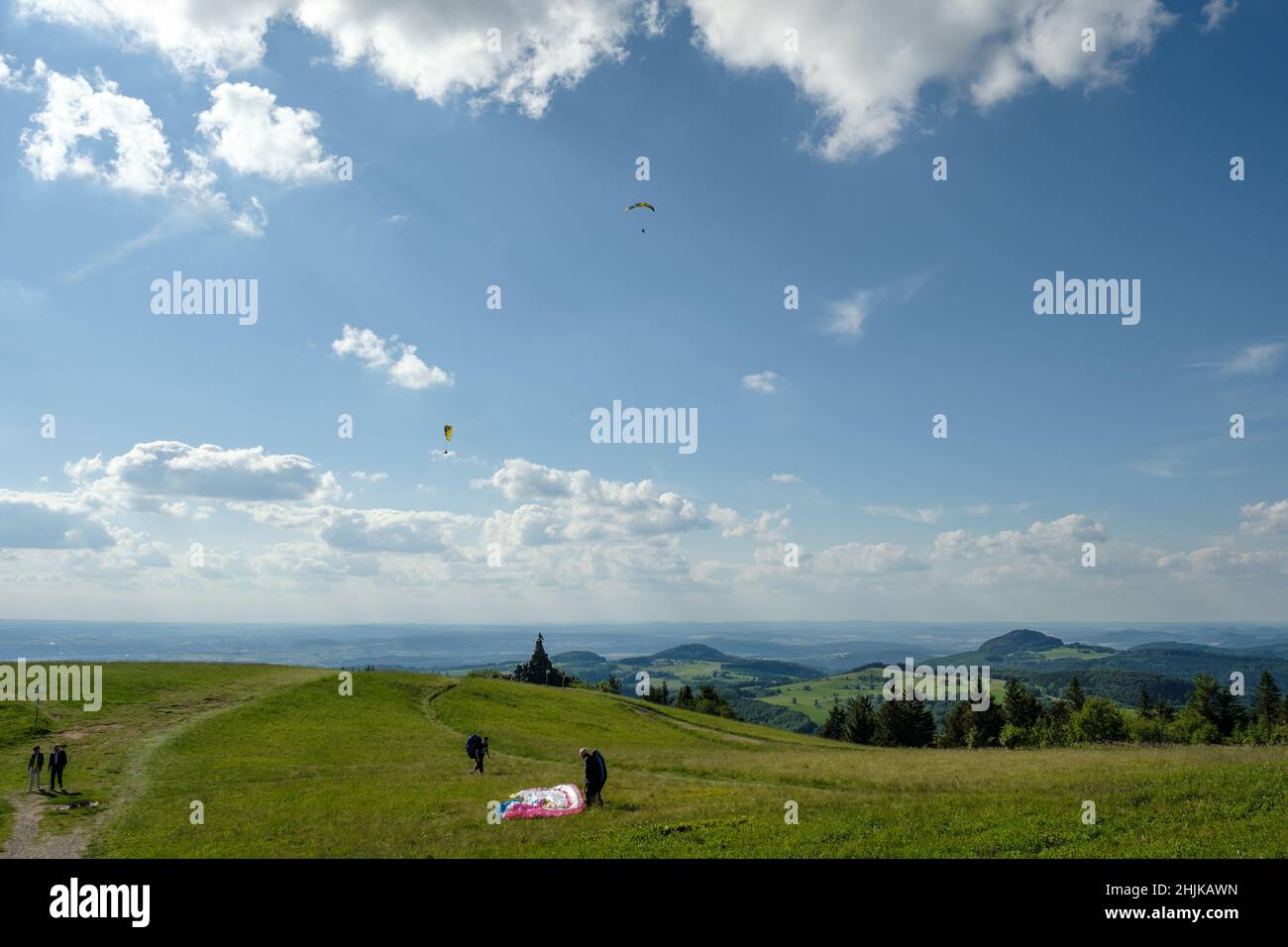 View from the hill Wasserkuppe in nature park Rhön Germany with paragliding on the ground and in the air. Stock Photo