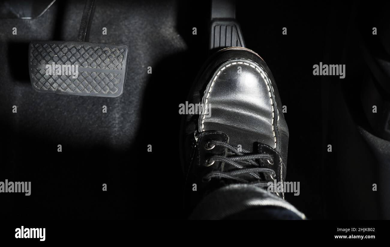 Accelerate and Brake. Foot pressing foot pedal of a car to drive ahead