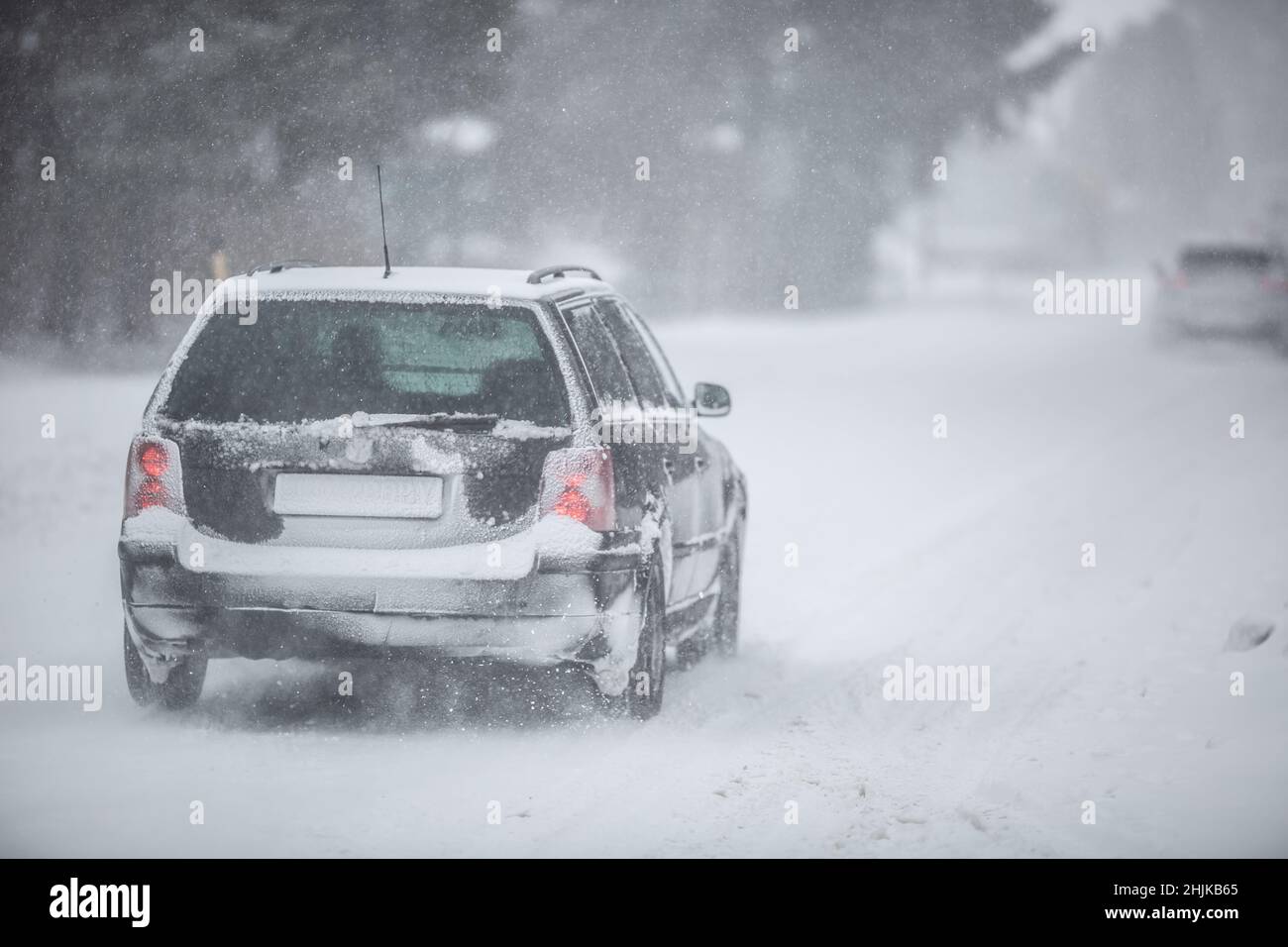 Liptov, Slovakia - JANUARY 30, 2022. Car covered in snow driving in snowstorm on a cold winter day. Stock Photo