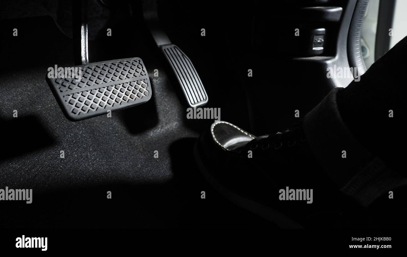 Accelerate and Brake. Foot pressing foot pedal of a car to drive ahead