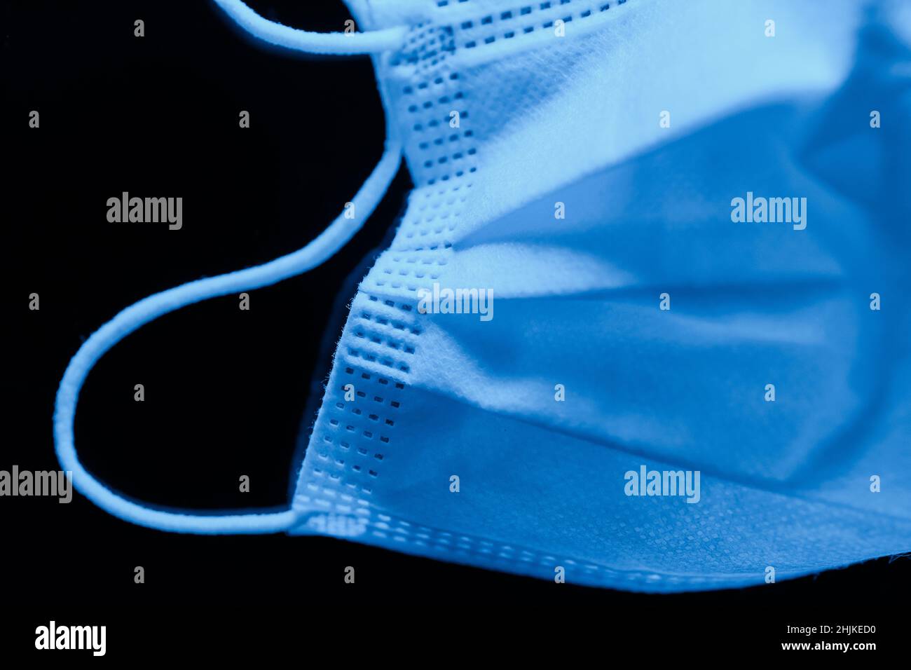 Surgical mask in deep ultramarine tones on dark background - macro shoot Stock Photo