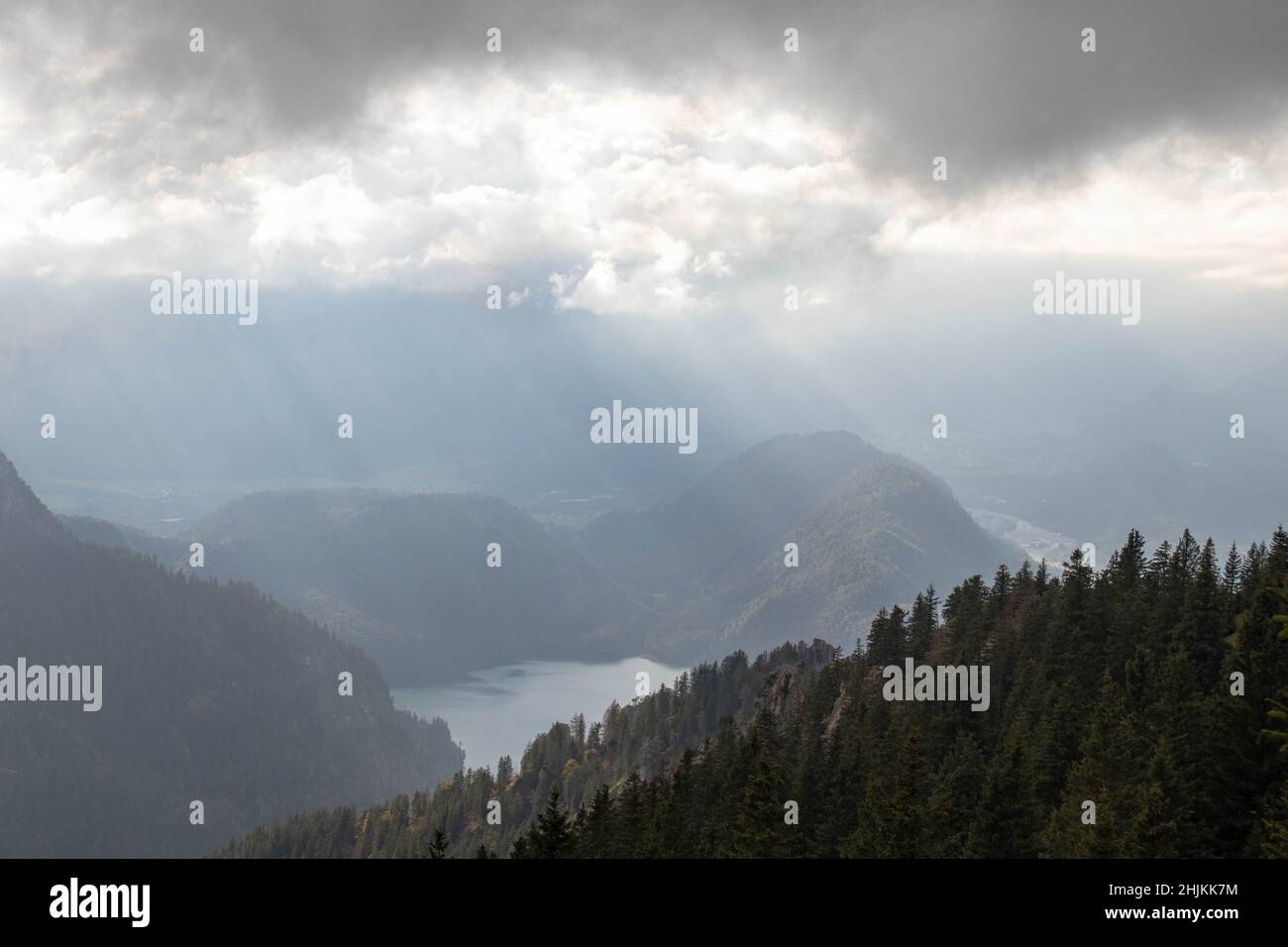 Sonnenstrahlen werden an den Wolken gebrochen. Blick auf den Alpsee und Hohenschwangau durch Wolken und Nebel Stock Photo